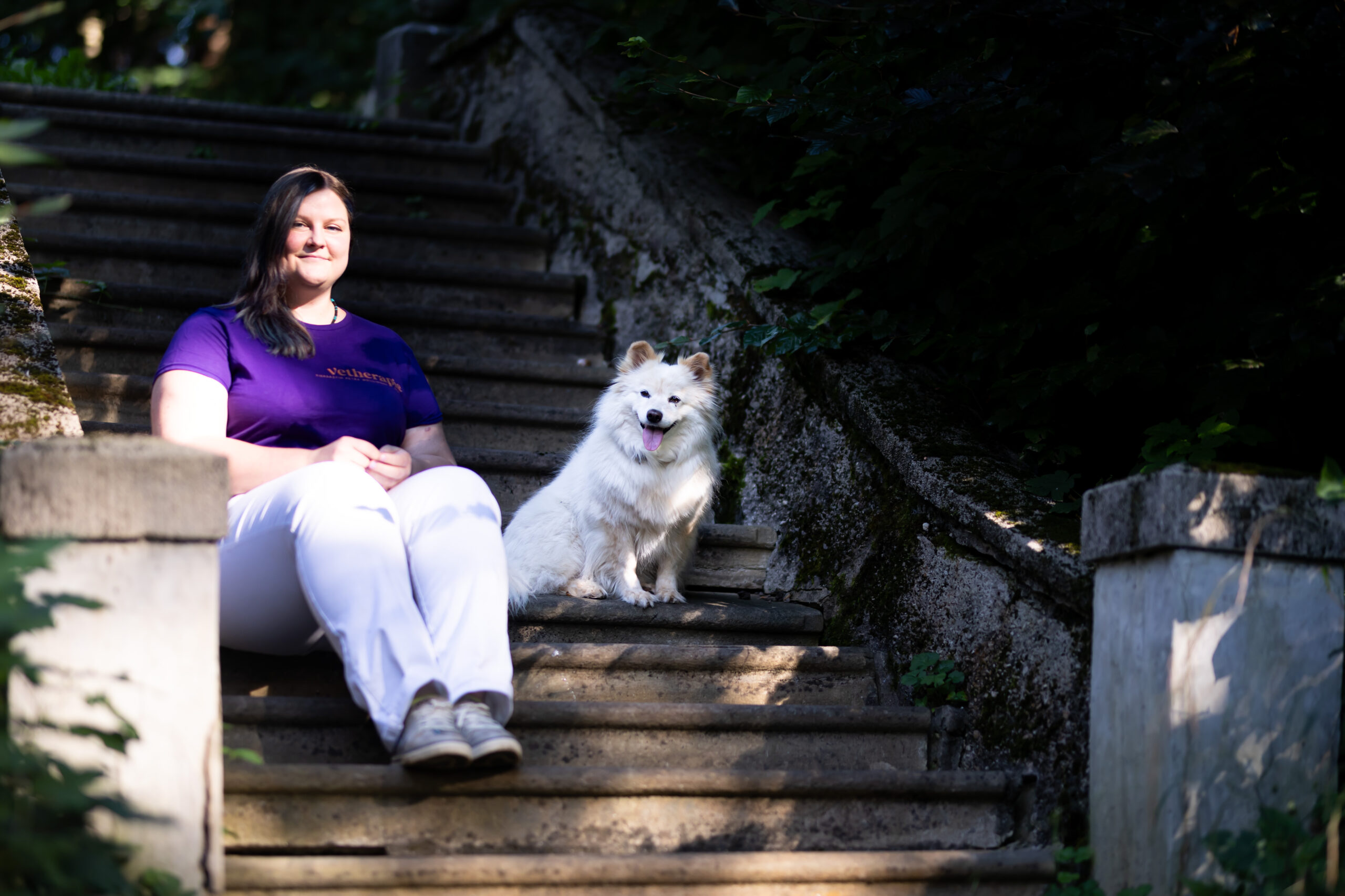 Petra Wollinger mit weißem Hund auf der Treppe sitzend Tierphysiotherapie